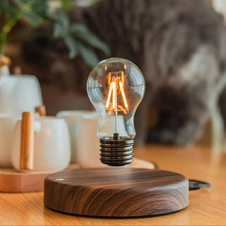 Lampe à poser bois et ampoule LED flottante magnétique, allumée et posée sur un meuble en bois à côté d'un service à thé en porcelaine blanche.