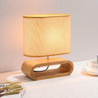 Lampe à poser bois style nordique à LED posée sur un meuble avec un livre à gauche et des épis de blé posés dessus et une tasse à droite