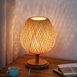 Lampe à poser bois style vintage à LED posée sur un meuble marron avec une tasse des livres et un rideau à gauche