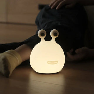 Lampe à poser enfant LED en forme de limace sur le sol avec un enfant derrière