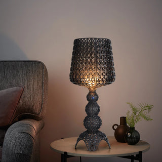 Lampe à poser vintage et design à LED posée sur une petite table avec des pots de fleurs et un canapé gris à gauche