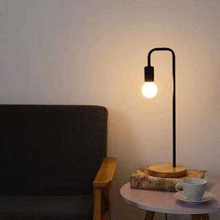 Lampe à poser vintage à LED avec socle en bois installée sur une petite table avec un livre et une tasse et avec un canapé à gauche