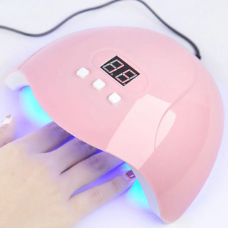 Lampe UV ongles à LED avec trois minuteurs sur fond gris avec la main d'une femme à l'intérieur