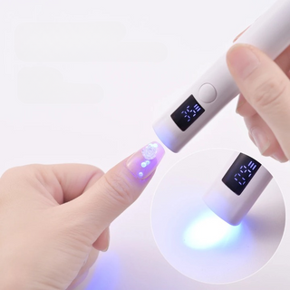 Lampe uv ongles portable avec séchage rapide à LED allumée sur l'ongle d'une femme